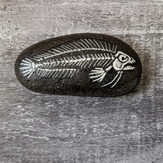 a rock with a fish skeleton painted on it