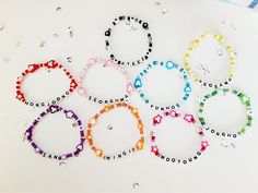 six bracelets with words written on them in different colors and sizes, all made up of plastic beads