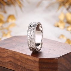 a silver ring with leaves on it sitting on top of a wooden box