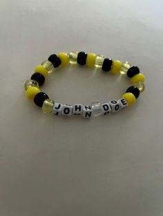 a yellow and black beaded bracelet with the word johnny written in white letters on it