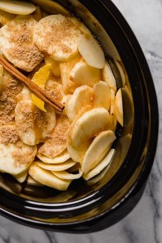 sliced apples and cinnamon in a slow cooker, ready to be cooked for dinner