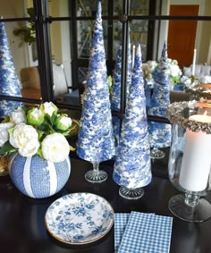 blue and white christmas decorations on a dining room table with candles, plates and napkins