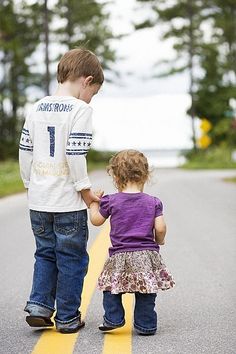 two children are walking down the street holding hands