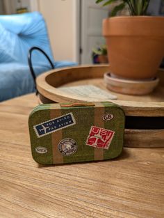 a small suitcase sitting on top of a wooden table next to a potted plant