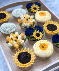 cupcakes decorated with sunflowers and blue flowers on a wooden platter