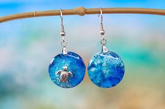 "Round asymmetric dangle earrings of the blue sea and a turtle in the sea. These coral reef effect earrings made with resin and with different shades of blue. Each piece of unique nautical jewelry is made with great delicacy and attention. Each earring is different, one representing the deep ocean and the other the beauty of a turtle in the sea. They are light and very original so they become the best gift. Each ocean round earrings is made with great finesse and no two are alike. So yours will Ocean-inspired Blue Earrings For Gifts, Blue Resin Earrings For Beach, Blue Resin Earrings For The Beach, Silver Round Resin Earrings, Resin Drop Earrings For Beach, Ocean-inspired Blue Resin Jewelry, Blue Ocean-inspired Resin Jewelry, Blue Round Pendant Earrings For Gift, Blue Round Pendant Earrings As Gift