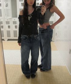 two young women standing in front of a mirror