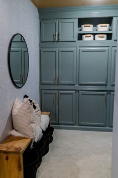 a room with blue cabinets and white rugs on the floor next to a wooden bench