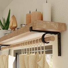 a wooden shelf with some curtains hanging from it's sides and candles on the other side