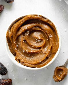 a white bowl filled with peanut butter surrounded by raisins