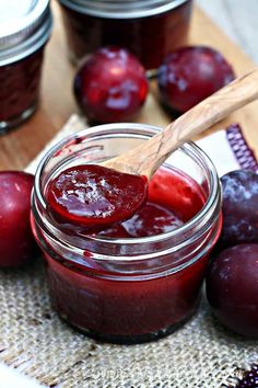 a jar filled with jam next to sliced plums