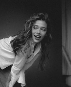 a black and white photo of a woman with her hair blowing in the wind, smiling