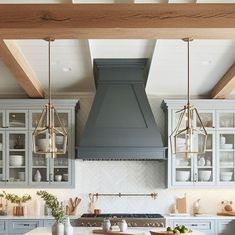 a kitchen with gray cabinets and white counter tops, an island in the middle is surrounded by hanging lights