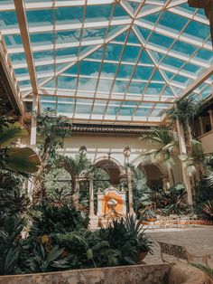 the inside of a large building with lots of greenery and palm trees in it