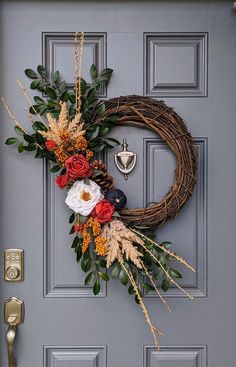 a wreath is hanging on the front door with flowers and greenery in fall colors