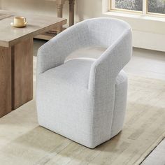 a white chair sitting on top of a wooden floor next to a table and window