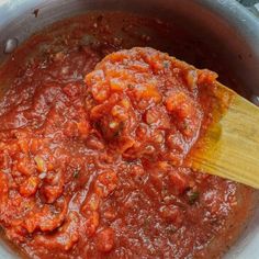 a wooden spoon in a pot filled with sauce