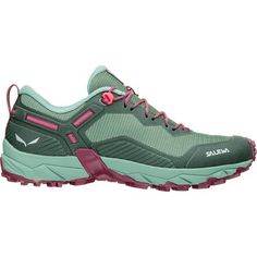 a woman's hiking shoe with pink laces on the side and green upper part