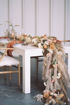 a long table with flowers and feathers on it is set up for a dinner party