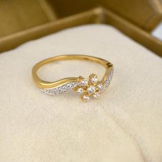 a gold ring with white stones in it sitting on a velvet cushioned surface next to an open box