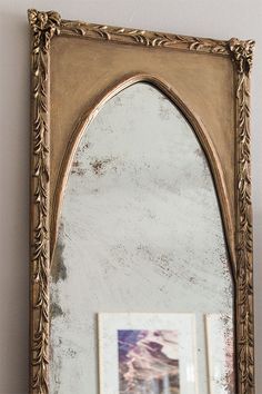 an ornate gold framed mirror hanging on the side of a wall next to a vase