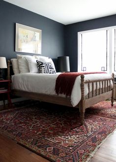 a bed sitting on top of a wooden floor next to a window in a bedroom