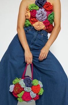 a woman is sitting on the floor holding a handbag with multicolored flowers