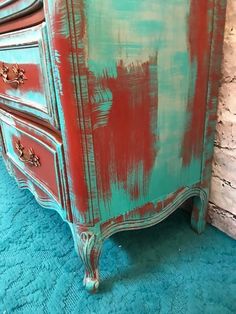 an old dresser is painted red and green