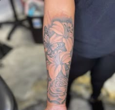 a person with a tattoo on their arm holding a cell phone in one hand and a flower in the other