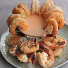 a white plate topped with cooked shrimp and dipping sauce on top of the food items