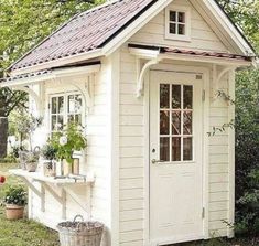 a small white shed with a red roof