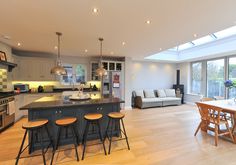 a large open kitchen and living room area with an island in front of the dining table