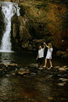 two people standing in front of a waterfall