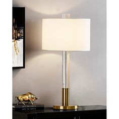 a table lamp with a white shade on it and a gold pig figurine next to it