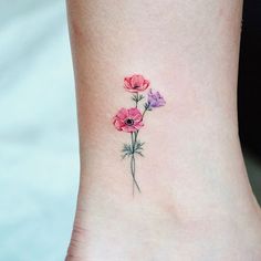 a small ankle tattoo with three flowers on the left side of the ankle and one flower in the middle