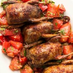 grilled chicken with tomatoes and herbs on a white plate, ready to be eaten