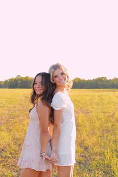 two young women standing next to each other in a field