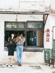 two people standing in front of a store window