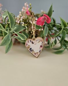 This beautiful floral pendant features real  flowers grown, dried, and pressed by me. The perfect flowers are set in a soft white resin and a gold colored heart bezel. This beautiful pendant comes with a gold chain measuring 20 inches in length. Some very minor imperfections may be noted due to the handmade nature of this product. Do not wear jewelry piece showering or swimming to keep it looking its best. White Heart Jewelry With Pressed Flowers, Elegant Pressed Flowers Jewelry For Valentine's Day, White Heart-shaped Jewelry With Pressed Flowers, Heart-shaped Birth Flower Necklaces For Wedding, Heart-shaped Birth Flower Necklace For Wedding, Wedding Heart-shaped Necklaces With Birth Flower, Gold Jewelry With Floral Print For Gift, Elegant Floral Print Jewelry For Gift, Elegant Floral Print Jewelry As Gift