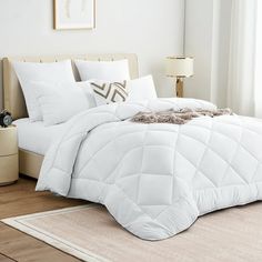 a bed with white comforter and pillows in a room