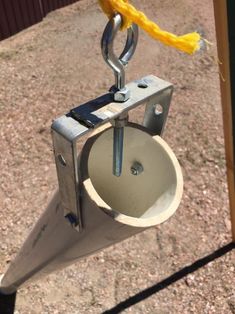 a metal object hanging from the side of a wooden pole next to a yellow rope