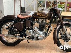 a brown and black motorcycle parked on top of a wooden floor next to a table