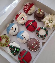 twelve decorated cupcakes in a white box with christmas decorations on the top and bottom