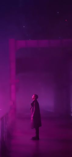 a person standing in front of a purple light with their back turned to the camera