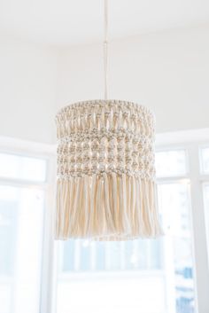 a white chandelier hanging from the ceiling in a room with two large windows