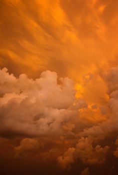 an airplane is flying in the sky with orange clouds behind it and another plane on the ground