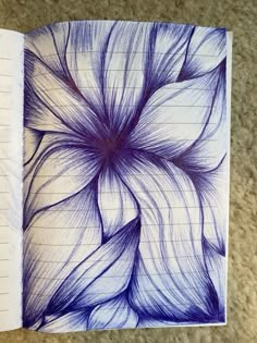 an open notebook with blue and white flowers drawn on the pages in front of it