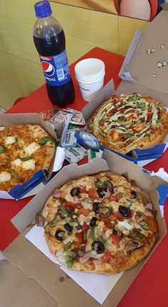 three pizzas sitting on top of a red table