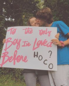 two people kissing each other while holding a sign that says to the only boy in love before hoo?