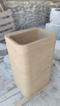 a square wooden container sitting on top of a table next to some wood planks